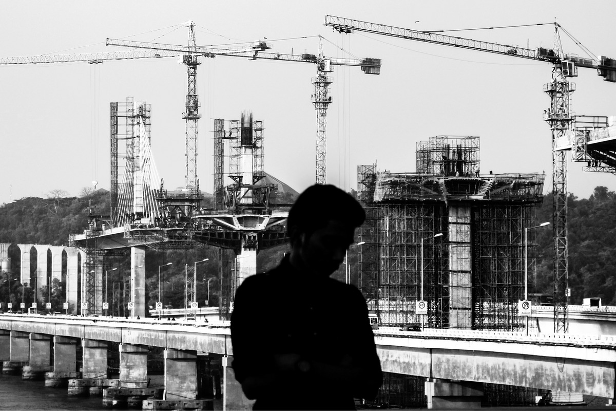 A project team reviewing data on a tablet in front of a crane.
