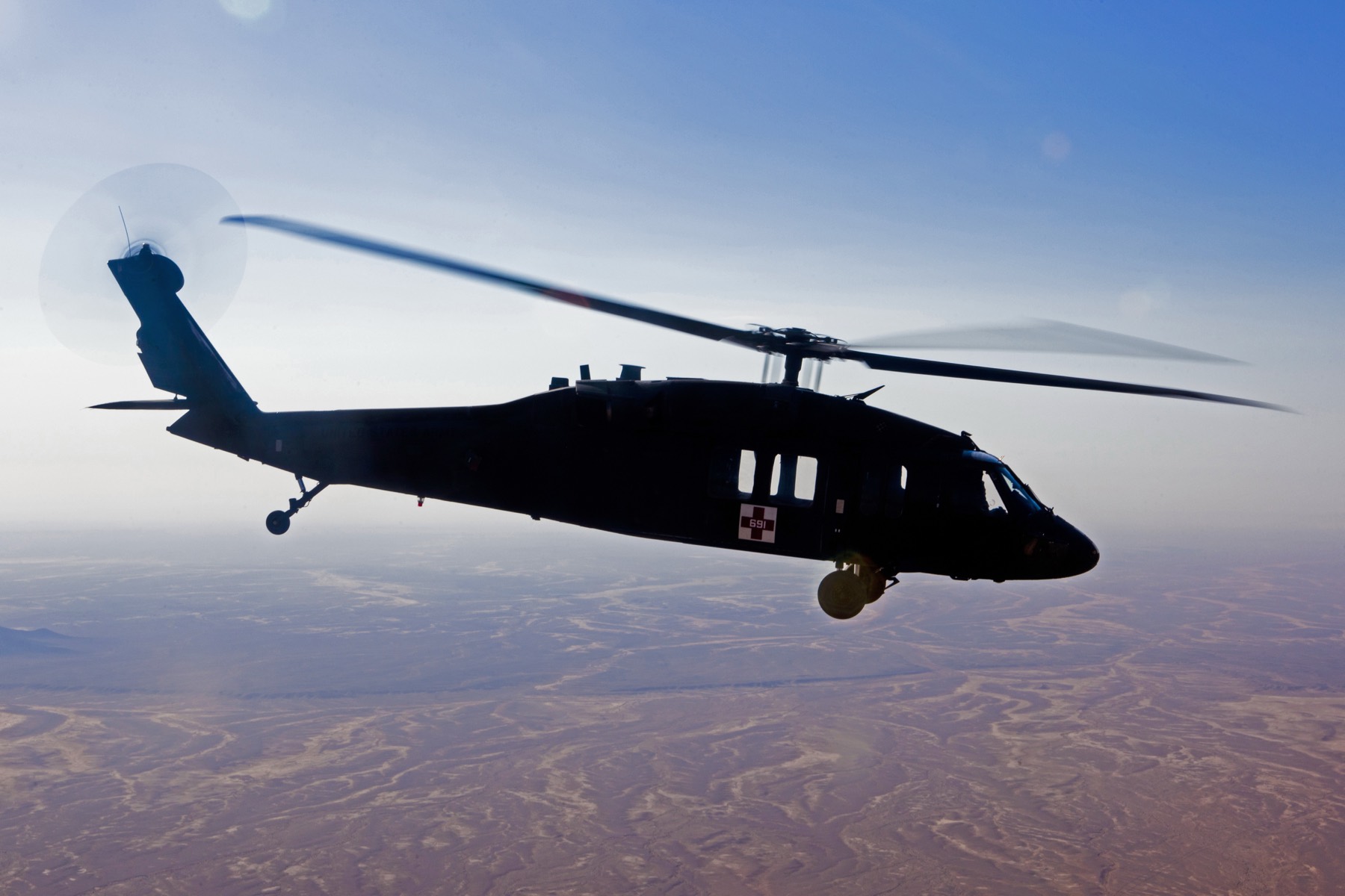 A medical evacuation helicopter in flight above open terrain