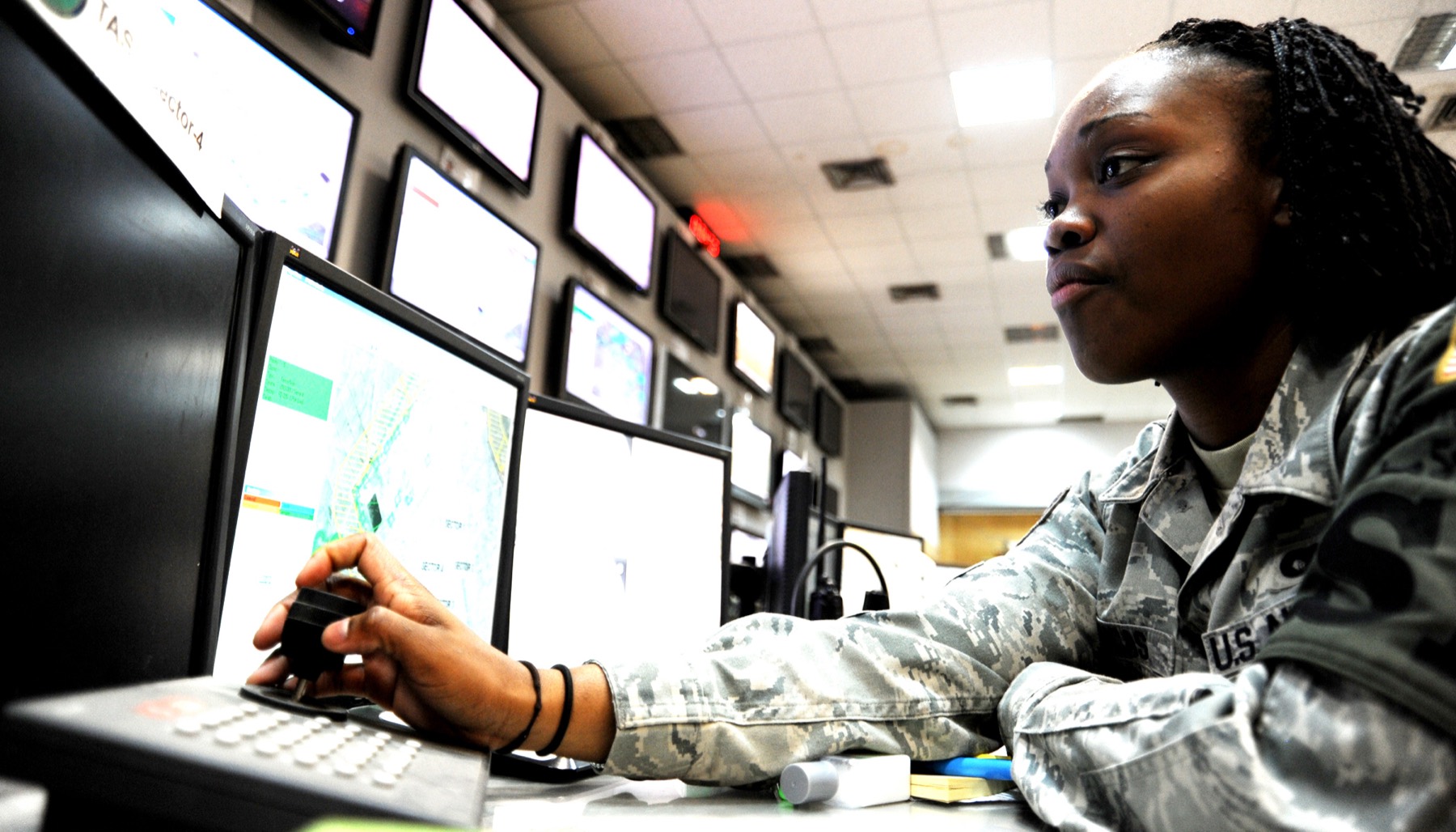 An analyst monitoring a wall of screens in an operations center