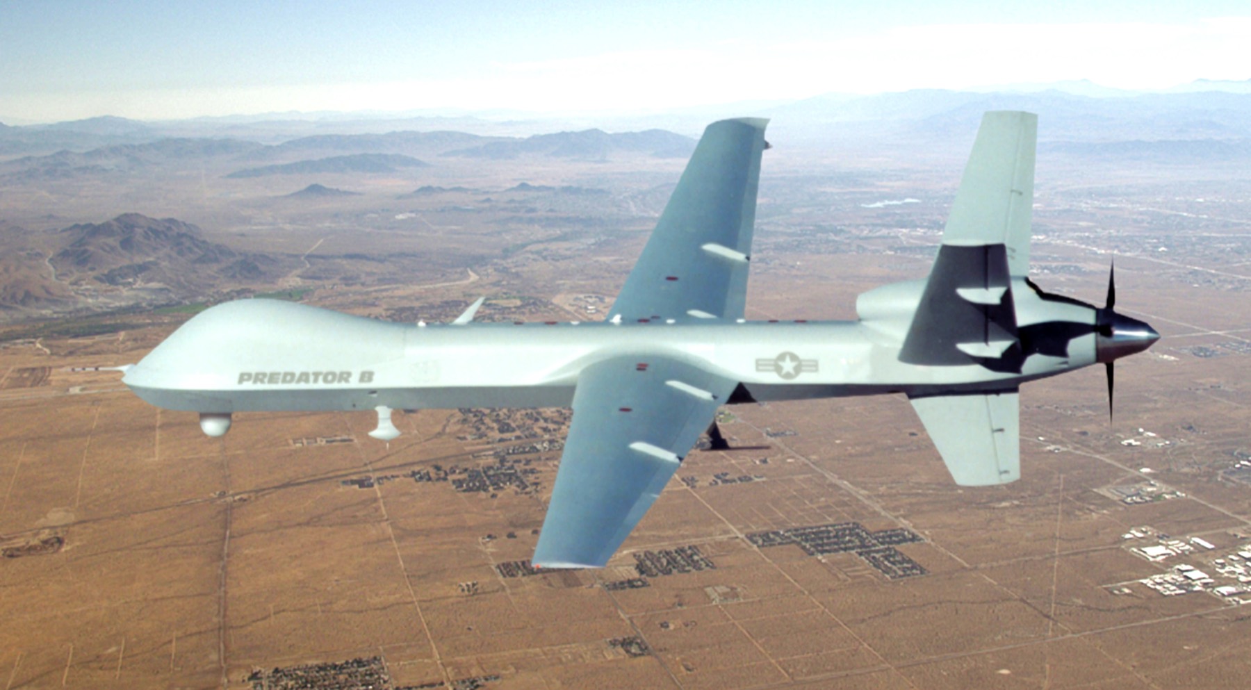 An uncrewed aircraft in flight over open terrain