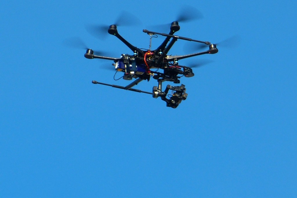 A black professional multirotor drone with a camera gimbal in flight, capturing high-resolution aerial site imagery.